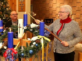 Charles Bolduc, left, congregational care co-ordinator of St. Peter's United Church, looks on as Rev. Dawn Vaneyk, minister of St. Peter's, lights candles located around a wreath at the church in Sudbury. The congregation is honouring First Nations spirituality in its rituals during the Advent/Christmas season. The wreath is shown with ribbons reflecting a medicine wheel with colours of the four seasons. John Lappa/Sudbury Star/Postmedia Network