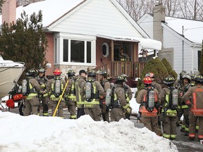 Toronto firefighters stand in the driveway after a two-alarm blaze was brough under control in a house on Phyllis Ave., near McCowan and Kingston Rds. area. (John Hanleyé Special to the Sun)