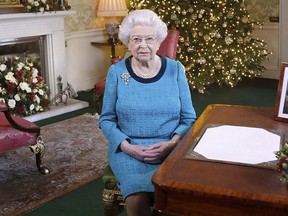 In this photo released early Sunday Dec. 25, 2016, Britain's Queen Elizabeth II poses for a photo, sitting at a desk in the Regency Room of Buckingham Palace in London, after recording her traditional Christmas Day broadcast to the Commonwealth. (Yui Mok/Pool via AP)
