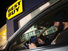 Martin Norry sits in his car and watches a movie on a tablet as he waits for the Best Buy in South Edmonton Common to open, in Edmonton Sunday Dec. 25, 2016.David Bloom/Postmedia