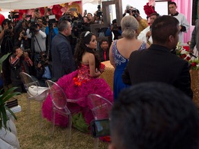 Rubi Ibarra looks at her mother Anaelda as journalists struggle to get images during a Mass as part of Rubi's down-home 15th birthday party in the village of La Joya, San Luis Potosi State, Mexico, Monday, Dec. 26, 2016. Millions of people responded to the invitation for Rubi's Dec. 26th coming of age party in rural northern Mexico, after her parent's video asking "everybody" to attend went viral.(AP Photo/Enric Marti)