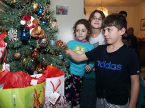 Nour Alzahran, 10, decorates a Christmas tree at the family's house in Capreol as sisters Rama, 4, left, and Hanan, 6, look on. (John Lappa/Sudbury Star)