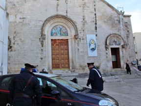 Carabinieri paramilitary police stand front of the entrance of the Chiesa Madre (Mother Church) where a Mass in memory of a Canadian crime clan boss Rocco Sollecito was supposed to be held, in Grumo Appula, a village near Bari, southern Italy, Tuesday, Dec. 27 2016. (Annamaria Loconsole/ANSA via AP)