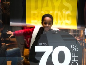 Henok Bekele, 5 escapes for his sister's who were minding their phones, into the display window of a men's clothing shop at White Oaks Mall in London, on Boxing Day. Bekele, froze like a mannequin once he was spotted. (MIKE HENSEN, The London Free Press)