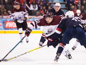 Latvia's Martins Dzierkals drives past the United States' Caleb Jones during IIHF World Junior Championships action in Toronto on Dec. 26, 2016. (THE CANADIAN PRESS/Nathan Denette)