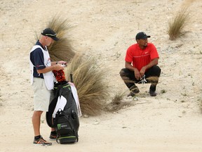 Tiger Woods of the United States and caddie Joe LaCava look on before playing his second shot on the third hole during the final round of the Hero World Challenge at Albany, The Bahamas on Dec. 4, 2016 in Nassau, Bahamas. (Christian Petersen/Getty Images)