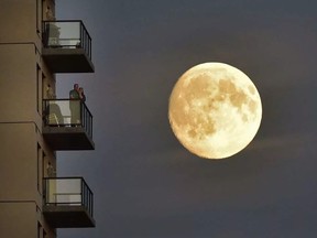 Two people on their balcony watch the FC Edmonton game at Clark Field as the waxing gibbous (94 per cent full) moon rises behind them on Wednesday, September 14, 2016.  ED KAISER / EDMONTON JOURNAL
