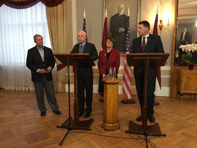 Latvian President Raimonds Vejonis, right, looks at  U.S. Sen. John McCain, centre left, during a press conference, Wednesday, Dec. 28, 2016, in Riga, Latvia, while Lindsey Graham, R-SC., and Amy Klobuchar, D-Minn., stand in the background. (AP Photo/Vitnija Saldava)