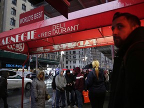 People wait in line to eat at the Carnegie Delicatessen in New York, Thursday, Dec. 29, 2016. After 79 years of serving up heaps of cured meat, the Carnegie slices its last ridiculously oversized sandwich Friday. (AP Photo/Seth Wenig)