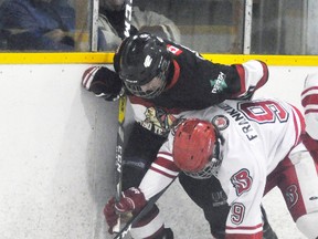 Kyle Spence (18) of the Mitchell Hawks is pinned to the end boards by this Hanover Baron during PJHL action in Mitchell Dec. 29th. The Hawks scored four goals in the first two periods en route to a 10-4 rout of their opponents. ANDY BADER/MITCHELL ADVOCATE