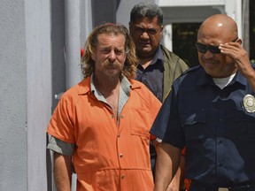 In this Oct. 4, 2016, file photo provided by the Samoa News, Dean Jay Fletcher, left, is escorted by a police officer after his initial appearance in the District Court of American Samoa in Pago Pago, American Samoa.