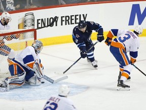 Winnipeg Jets' Bryan Little (18) attempts the wraparound on New York Islanders goaltender Thomas Greiss (1) as Nick Leddy (2) and Travis Hamonic (3) defend during first period NHL action in Winnipeg on Saturday, December 31, 2016. THE CANADIAN PRESS/John Woods