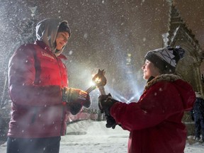 Blaze Belaire (right) lights a torch of Olympic swimming gold medalist Penny Oleksiak during the Fire of Friendship relay of the New Year's Eve celebration on Parliament Hill, Saturday, Dec. 31, 2016 in Ottawa. Canada celebrates its 150th anniversary of Confederation in 2017.