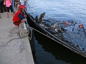 A man inspects the wreckage of a ferry that caught fire off the coast of Jakarta, at Muara Angke Port in Jakarta, Indonesia, Sunday, Jan. 1, 2017. (AP Photo/Dita Alangkara)