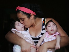 Mother Raquel Barbosa poses holding her twin daughters Eloisa (L) and Eloa, both 8 months old and both born with microcephaly, on Christmas day during a celebration at the twin's grandparent's home on December 25, 2016 in Areia, Paraiba state, Brazil. (Photo by Mario Tama/Getty Images)