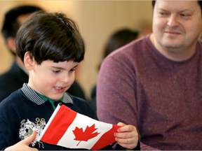 Five-year-old Henri Radimov, holds his new flag while his father, Nikolay, proudly looks on after the Ukraine family received their citizenship certificates. (Julie Oliver, Postmedia)