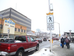 Pedestrians walk past the new crossover on Elm Street on Tuesday. Some walkers and motorists are finding the system baffling and dangerous, as a button must be pushed halfway across the street in order to keep the yellow lights flashing. (Gino Donato/Sudbury Star)