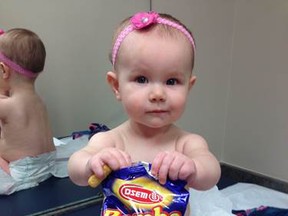 In this photo provided by the Carrie Stevenson, her daughter Estelle holds a bag of peanut snacks in her pediatrician’s office at age nine-months, in Columbus, Ohio. Most babies should start eating peanut-containing foods well before their first birthday, say guidelines released Thursday that aim to protect high-risk tots and other youngsters, too, from developing the dangerous food allergy. The new guidelines from the National Institutes of Health mark a shift in dietary advice, based on landmark research that found early exposure dramatically lowers a baby's chances of becoming allergic. (Carrie Stevenson via AP)
