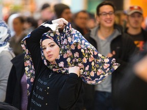 A woman adjusts her hijab amidst a crowd of busy shoppers. (Mike Hensen/Postmedia Network)