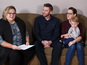 Sean Collins (centre), Rene Beaulac (right), and their son Bo Collins, 18-months-old, listen as Deputy Premier Sarah Hoffman speaks about the carbon levy during a press conference at the family's home in Edmonton, Alberta on Thursday, January 5, 2017. Ian Kucerak / Postmedia