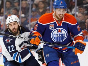 Adam Larsson of the Edmonton Oilers, right, battles against Chris Thorburn of the Winnipeg Jets on December 11, 2016 at Rogers Place in Edmonton.