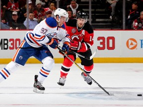 Connor McDavid of the Edmonton Oilers, left, takes the puck as Adam Henrique of the New Jersey Devils defends in the first period on February 9, 2016 at Prudential Center in Newark, New Jersey.