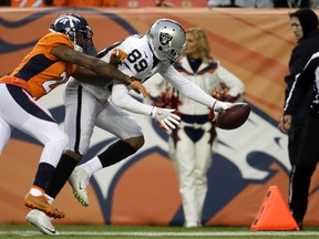 Raiders wide receiver Amari Cooper (right) dives towards the end zone for a touchdown ahead of Broncos cornerback Aqib Talib (left) during NFL action in Denver on Sunday, Jan. 1, 2017. (Joe Mahoney/AP Photo)