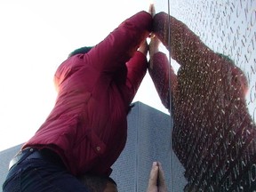 National Guardsman Joseph Mott gives his wife Dana a lift at the Vietnam Veterans Memorial as she does a rubbing of the name of one of her father's comrades.  (Toronto Sun files)