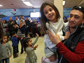Yasser Jakl dances with daughter Estervan, 4, during a celebration marking the first anniversary of the arrival of Syrian refugees in Winnipeg. (KEVIN KING//Winnipeg Sun)