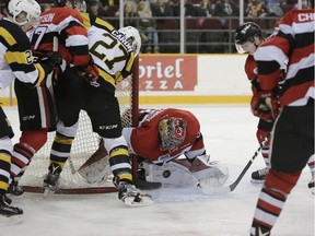 Ottawa 67’s goalie Leo Lazarev tries to cover the bouncing puck as Kingston Frontenacs forward Cody Caron looks on during Ontario Hockey League action at TD Place in Ottawa on Saturday afternoon. (David Kawai/Postmedia Network)