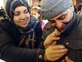 LUKE HENDRY/THE INTELLIGENCER 
Raghda Al Mansour affixes a Canadian flag pin to the jacket of her husband, Mohamed Hamada, in the Islamic Society of Belleville's mosque Sunday. They and their three young children arrived in the city Dec. 28.