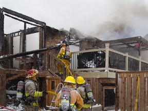 Volunteer firefighters from Coldstream haul a hose up to the heavily damaged rear of a home at 10 Wynfield Lane in Melrose on Sunday. Crews from Arva, Ilderton and Coldstream responded to the blaze. (MIKE HENSEN, The London Free Press)