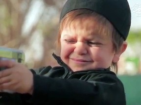 A toddler takes aim at an ISIS prisoner in this video screengrab.