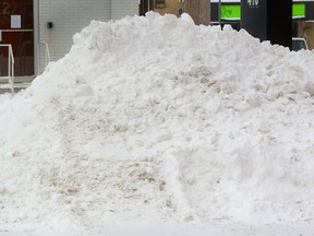 A pedestrian with a shovel walks past a pile of snow in a parking lot on Wharncliffe Ave on Monday January 9, 2017 (MORRIS LAMONT, The London Free Press)