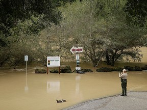 A Sonoma County Sheriff's officer takes a photo of the Russian River as it flows through a beach park Monday, Jan. 9, 2017, in Monte Rio, Calif. (AP Photo/Eric Risberg)