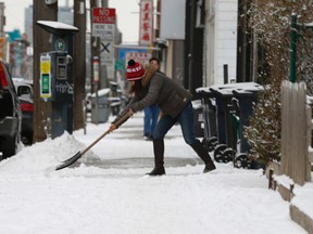 A woman shovels the snow from the sidewalk at Gerrard St. E. and Howland Rd. after a light early morning snowfall on Tuesday, January 10, 2017. (Jack Boland/Toronto Sun)