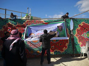 Palestinians hang a banner at a mourning tent being set up for Fadi Qunbar, in east Jerusalem, Monday, Jan. 9, 2017. Qunbar was killed after he drove a truck into a group of Israeli soldiers Sunday killing four and and injuring 17 others. Israeli police said they have arrested nine people, five of them relatives of 28-year-old Qunbar. Banner bearing Qunbar's photo reads, "Arab tribes of Sawahreh and Qunbar, family" and "Palestinian people mourn the martyr hero Qunbar." (AP Photo/Mahmoud Illean)