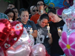 In this Aug. 25, 2016 file photo, from left to right, Nicole Maldonado, Myriah Flores, and her mother Sharlene Benavidez attend a candlelight vigil for 10-year-old Victoria Martens at the apartment complex, in Albuquerque, N.M., where the young girl lived and was killed. Martens was strangled to death on her 10th birthday before she was dismembered and her remains set on fire, according to an autopsy released months after police uncovered the sexual abuse they say she suffered at the hands of her mother and others leading up to her killing. (Jim Thompson /The Albuquerque Journal via AP, File)