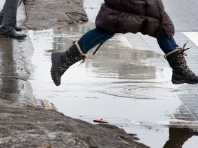 A pedestrian leaps over a puddle.
