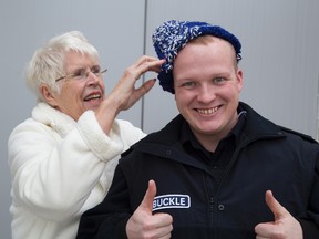 Valda Parenuik puts a hat that she crocheted on the head of police cadet Travis Buckle. Parenuik donated a dozen hats to Buckle who will be giving them to people in need. (DEREK RUTTAN, The London Free Press)