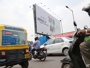 Motorists ride past a billboard advertising an Amazon product in Bangalore, India, Thursday, Jan. 12, 2017. India's foreign minister has demanded an apology from online retail giant Amazon.com Inc. for selling doormats depicting the Indian flag through its Canadian retail website. (AP Photo/Aijaz Rahi)