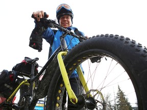 Guy Rouleau stands over his fat bike, which he is riding from Quebec City to Windsor to raise money for Kids Help Phone and to promote a Canada 150 event he is planning. He passed through Kingston on Wednesday. (Elliot Ferguson/The Whig-Standard)
