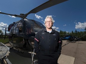 Paul Spring, a helicopter pilot and owner of Phoenix Heli-Flight, poses next to one of his helicopters south of Fort McMurray, Alta. on June 3, 2016. Greg Southam/Postmedia Network