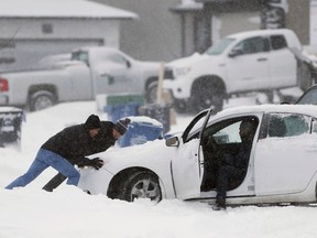 People push a stuck car after two days of snow in Winnipeg, Wednesday, Dec. 7, 2016. It's the dead of winter and despite how ominous that might sound the country's top climatologist says that's actually a good thing. (THE CANADIAN PRESS/John Woods)