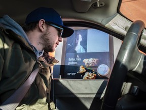 Josh McIlravey places his order at the drive-thru and is able to see who he is chatting with. There is a new Video screen that shows barista on the menu board at a Calgary Trail Starbucks drive-through on January 12, 2017. For story on this new piece of fast-food technology and what fast-food industry doing to attract customers. Shaughn Butts/Postmedia News