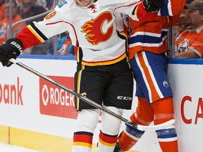 Brandon Davidson, right, of the Edmonton Oilers is taken to the boards by Matthew Tkachuk of the Calgary Flames on October 12, 2016 at Rogers Place in Edmonton, Alberta, Canada.