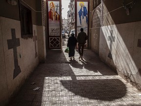 In this Tuesday, Jan. 6, 2015 file photo, Coptic Christians walk outside St. Markos Church in Minya, south of Cairo, Egypt. (AP Photo/Roger Anis, File)