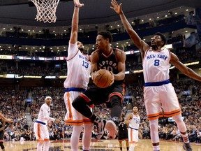 Toronto Raptors guard DeMar DeRozan passes off the ball as he is double teamed by New York Knicks centre Yoakim Noah and guard Justin Holiday (8) during first half NBA basketball action in Toronto on Sunday January 15, 2017. (THE CANADIAN PRESS/Frank)