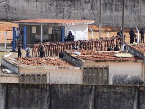 Naked inmates stand in line while surrounded by police after a riot at the Alcacuz prison in Nisia Floresta, Rio Grande do Norte state, Brazil, Sunday, Jan. 15, 2017. Security authorities said Sunday they have regained control of two Brazilian prisons after several inmates were killed during a riot, the latest in a string of prison disturbances across the country. (Frankie Marcone/Futura Press via AP)