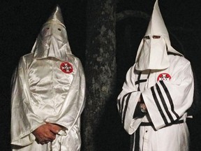 In this Friday, Dec. 2, 2016 photo, two masked Ku Klux Klansmen stand on a muddy dirt road during an interview near Pelham, N.C. (AP Photo/Jay Reeves)